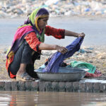 A nomad woman washing her clothes at the bank of a canal in the outskirts areas of the city.