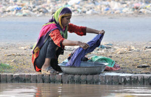 A nomad woman washing her clothes at the bank of a canal in the outskirts areas of the city. 