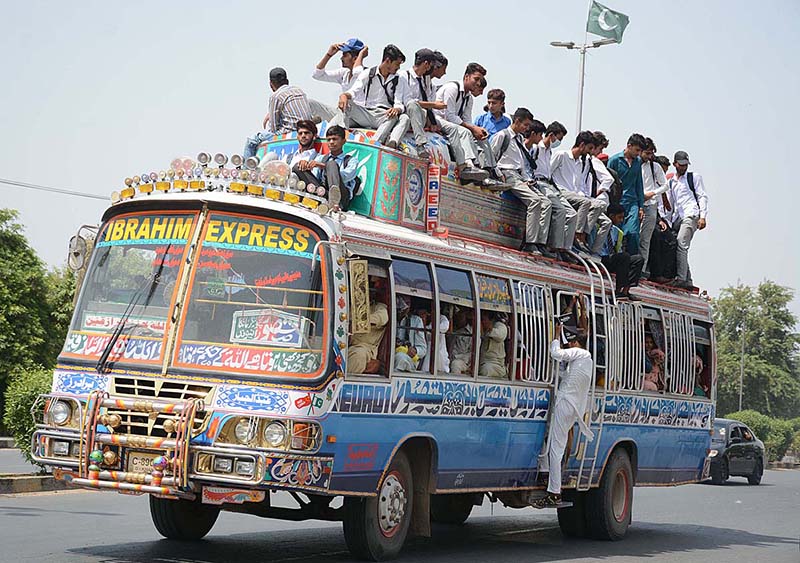 Students are engaging in risky behavior by traveling on the rooftop of a passenger bus, which may cause any mishap and needs the attention of concerned authorities