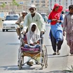 An elderly person pushing wheel chair of a disabled girl towards his destination