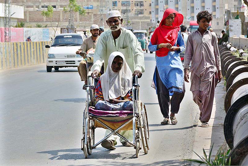 An elderly person pushing wheel chair of a disabled girl towards his destination