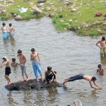 Youngsters jumping and bathing in the Rawal dam adjacent Nallah in the Federal Capital.