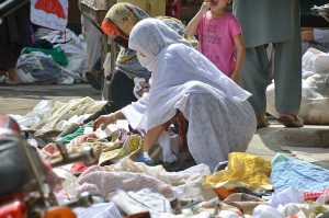 Female customers selecting and purchasing second hand clothes from roadside vendor at Hashtnagri area.