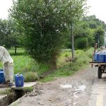 A man is filling his water cans with drinking water from a hand pump