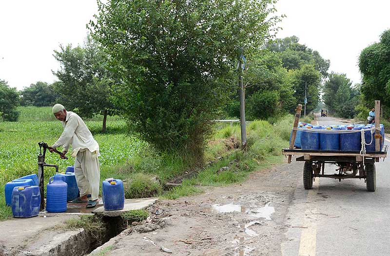 A man is filling his water cans with drinking water from a hand pump