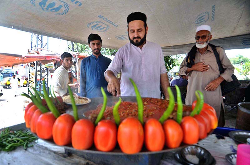 A vendor preparing traditional food item to attract customers at his roadside setup in the Federal Capital