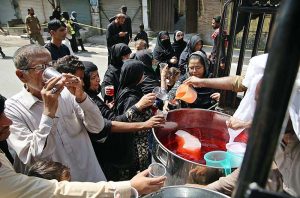 A girl offering water to motorcyclist from sabeel during Chehlum procession to commemorate the martyrdom of Hazrat Imam Hussain (RA) grandson of Holy Prophet Muhammad (SAWW).