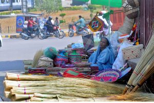A lady vendor displaying handmade household items while waiting for customers near Ghanta Ghar Chowk.