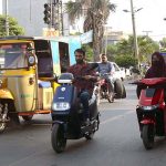 Woman riding Scooty on the way towards her destination.