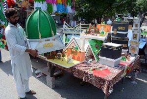 A vendor arranging and displaying Milad-un-Nabi (PBUH) related stuff to attract the customer at Aminpur Bazaar.
