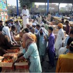Vendors displaying tomatoes boxes during an auction while shopkeepers participate in bidding at Vegetable Market