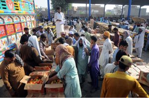 Vendors displaying tomatoes boxes during an auction while shopkeepers participate in bidding at Vegetable Market