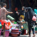 Ladies selecting and purchasing household plastic items for domestic use from a vendor