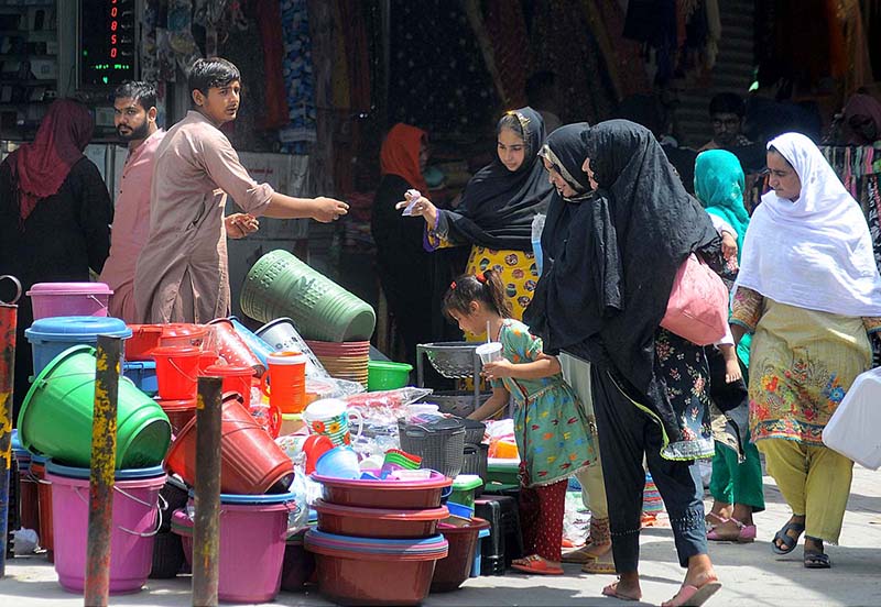 Ladies selecting and purchasing household plastic items for domestic use from a vendor