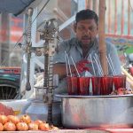 A vendor displaying and selling pomegranate juice at his roadside setup