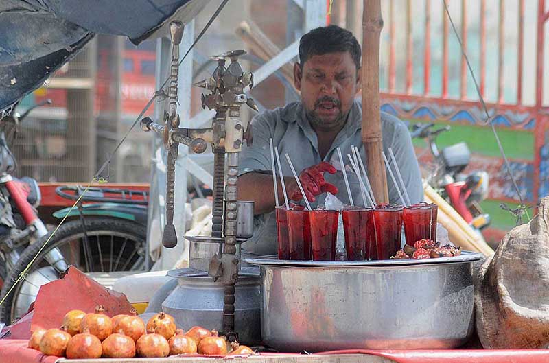 A vendor displaying and selling pomegranate juice at his roadside setup