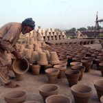 Worker busy in placing clay made pots for drying purpose in sunlight at his workplace
