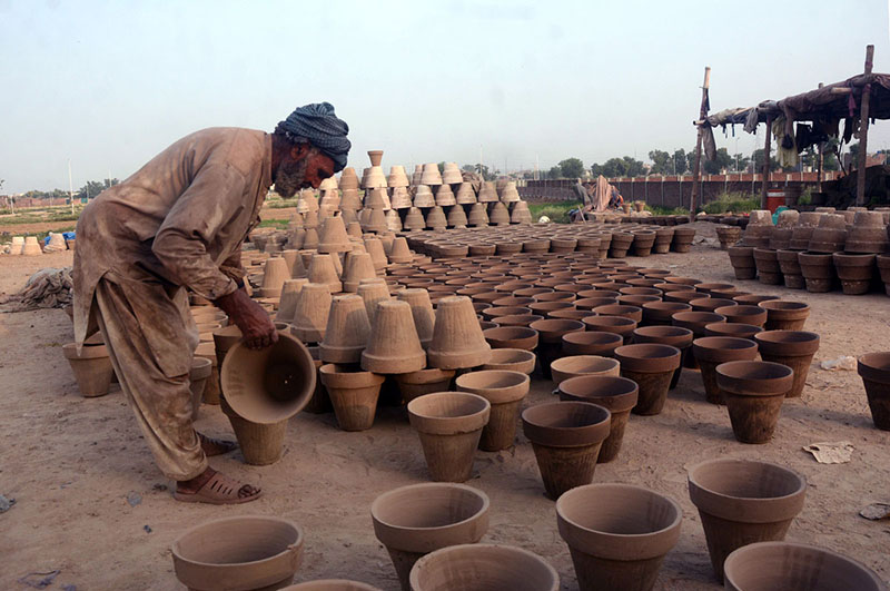 Worker busy in placing clay made pots for drying purpose in sunlight at his workplace