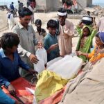 People purchasing ice from roadside vendor at Jamshoro area.