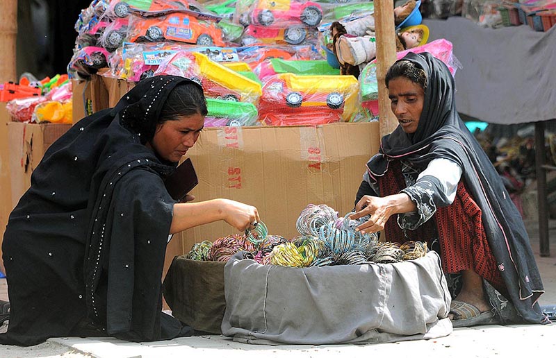 A woman selecting and purchasing bangles from roadside woman vendor at Shamsabad