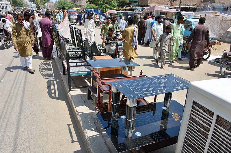 A vendor displaying the used furniture to attract the customers on the footpath at Latifabad