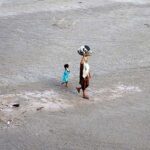 A woman on the way after washing the crockery at bank of Indus River.