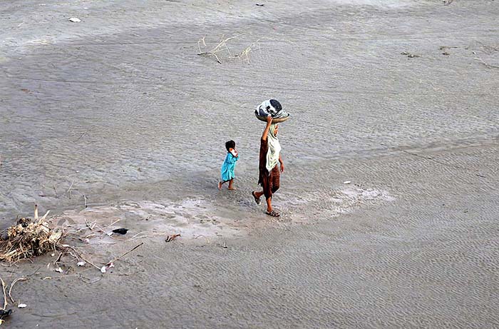 A woman on the way after washing the crockery at bank of Indus River.