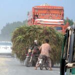 An overloaded motorcycle rickshaw with fodder for animals on the way violating the traffic rules and creating hurdles for smooth traffic flow at Head Muhammad Wala Road