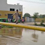 A boy is dangerously walking across a canal on a narrow pipe at Jhang Moor