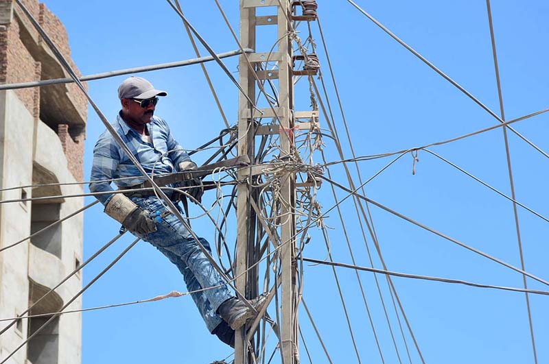 A lineman busy in cutting the illegal line of electricity during crackdown against illegal connections in the city