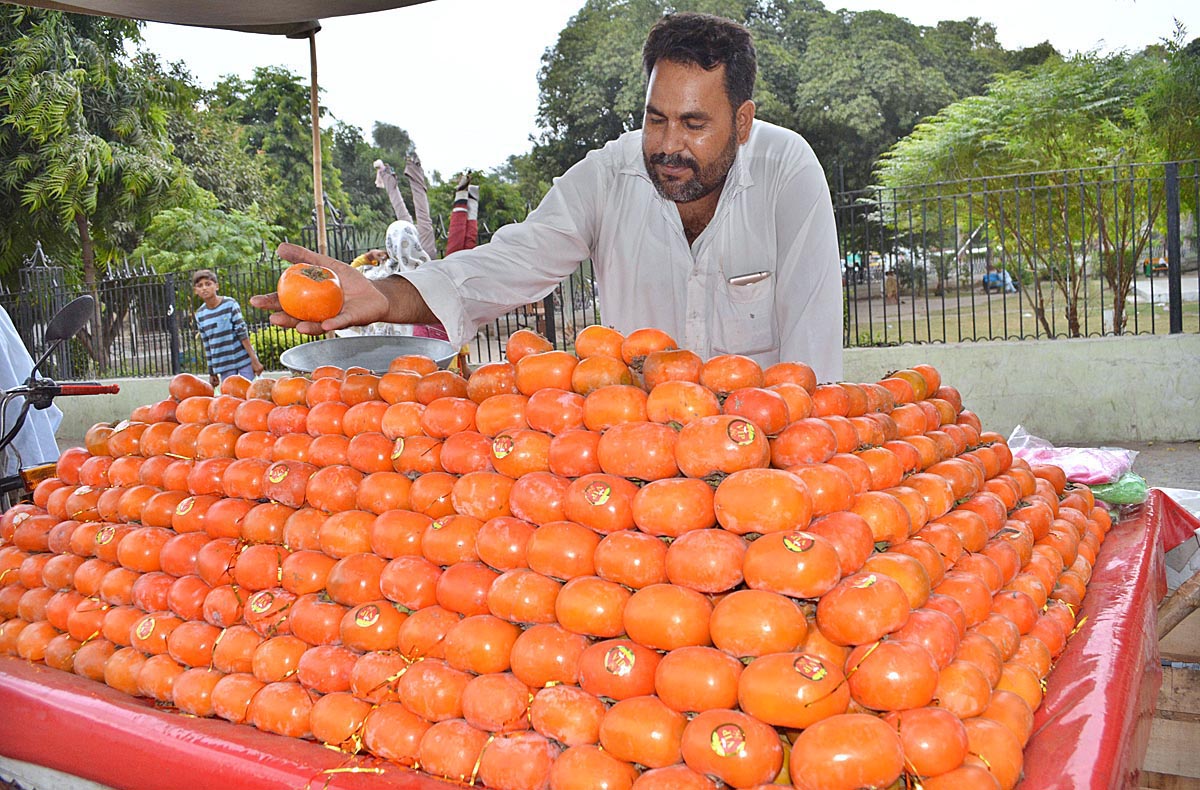 A vendor selling seasonal fruit on his cart.