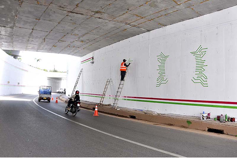 A Painter busy making different designs on the wall of Rawal underpass.