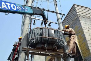 WAPDA staffers busy in installing power transformer on electric pole at Mohamdi Colony