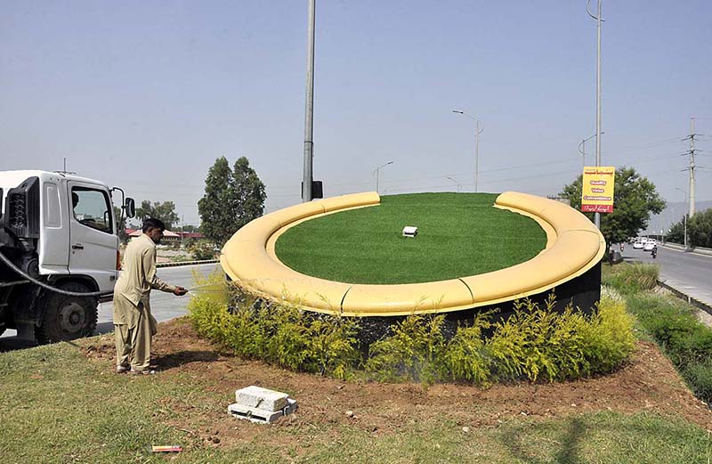 CDA worker busy in watering plants on greenbelt near H-9 flyover