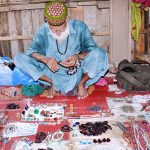An elderly vendor displaying precious stones to attract customers at his roadside setup