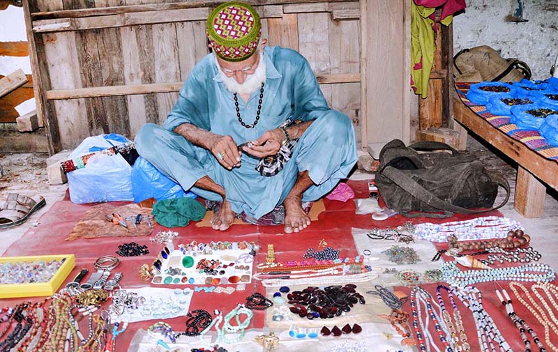 An elderly vendor displaying precious stones to attract customers at his roadside setup
