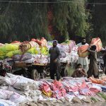 Labourers are loading bundles of plastic sacks after washing at the local canal