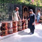 A vendor is selling carpets at a roadside stall