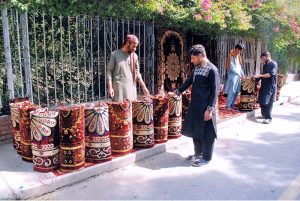 A vendor is selling carpets at a roadside stall
