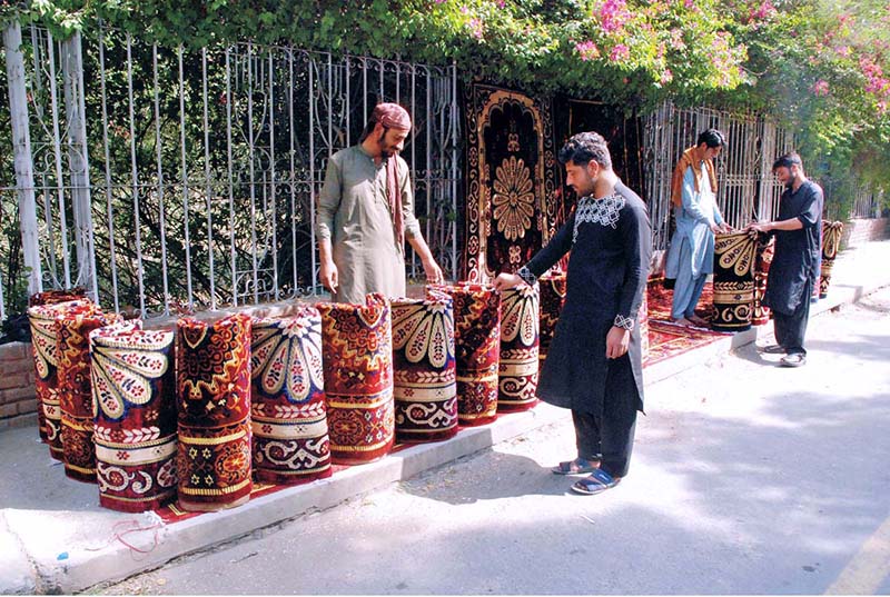A vendor is selling carpets at a roadside stall