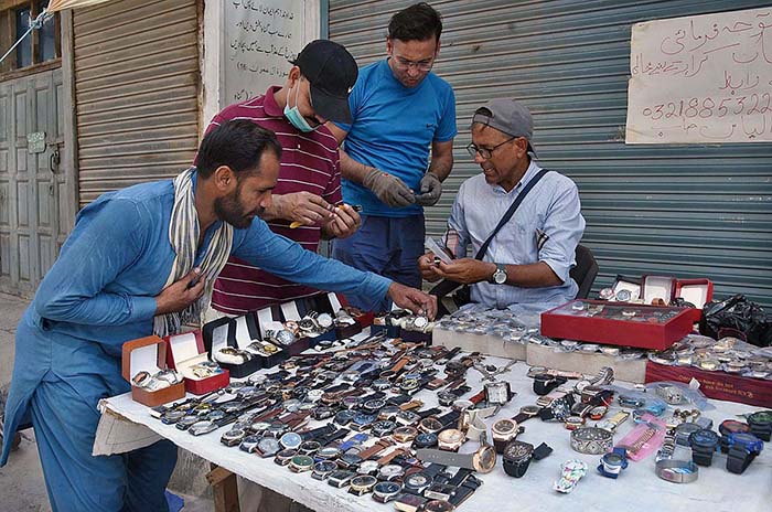 People are looking to buy watches at roadside in the city.