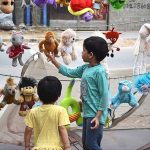 Children selecting old toys displayed by vendor at roadside stall