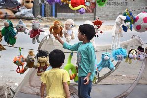 Children selecting old toys displayed by vendor at roadside stall