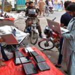A street vender displaying used laptops to attract the customers at his road side setup