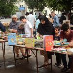 Customers selecting and purchasing old books from a roadside stall.