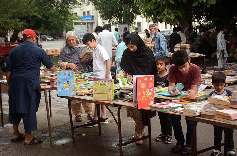 Customers selecting and purchasing old books from a roadside stall.