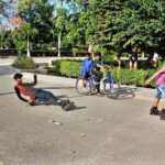 A boy, wearing skating shoes, is striking an acrobatic pose on the road