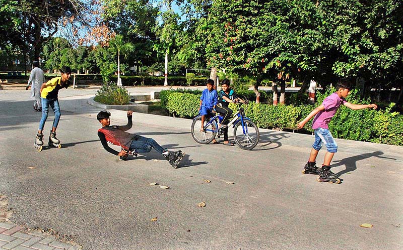 A boy, wearing skating shoes, is striking an acrobatic pose on the road