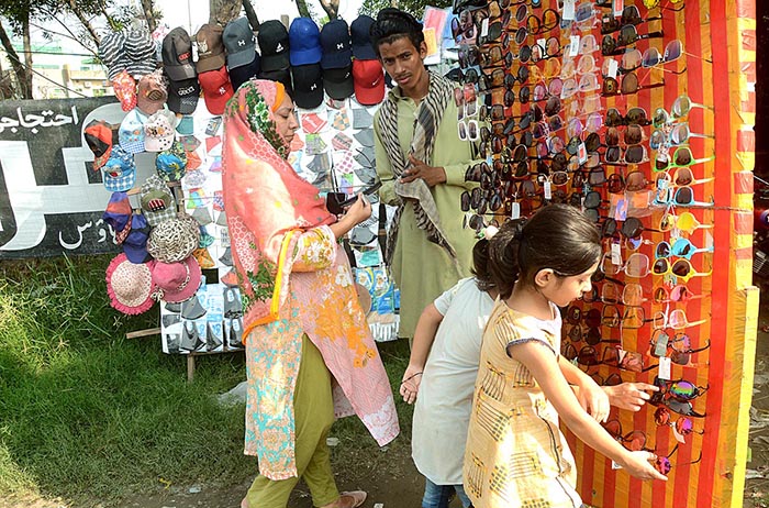 Vendor displaying Sunglasses to attract customers while shuttling on the road.