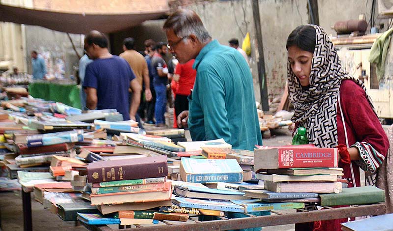 Customers selecting and purchasing old books from a roadside stall.